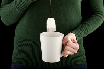 female hands holding a teacup and teabag