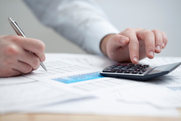 Financial data analyzing. Counting on calculator.