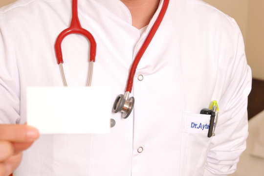 An image of a doctor with stethoscope holding business card.
