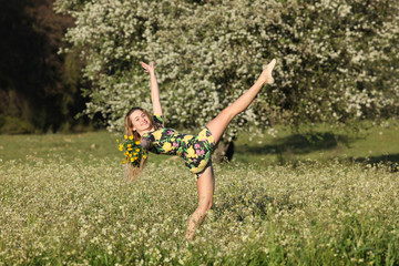 Beautiful young woman stretching in blooming meadow