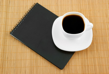 Fototapeta na wymiar Black spiral squared notebook with cup of coffee