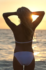 Fototapeta na wymiar Rear View Blond Woman On Beach In Bikini At Sunset