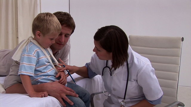 Assertive doctor examining a little boy's arm in hospital