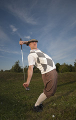Funny looking golfer stretches before swing from the rough.