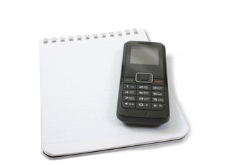 A blank notebook with a black phone on top