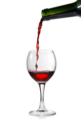 Pouring red wine in glass goblet isolated on white