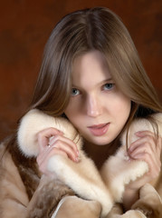 The girl in a fur coat on motley background