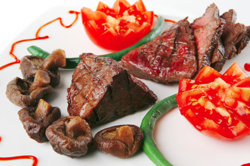 fillet mignon on a white plate and tomatoes