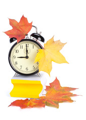 Alarm clock, autumn leaves and stacked  blank papers