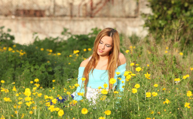 Obraz na płótnie Canvas Beautiful young woman sitting in meadow