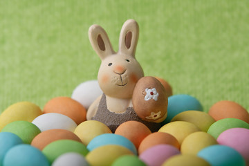 Easter bunny whit many colored easter eggs on a green background