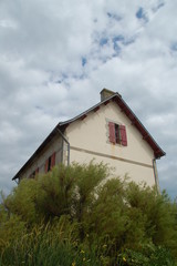 Maison isolée se découpant sur un ciel bleu avec nuages.