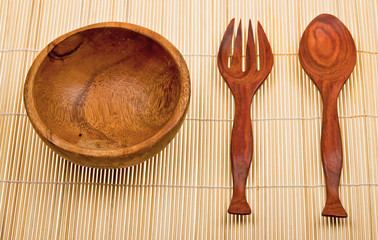 Wooden spoon, fork and basin on bamboo mat