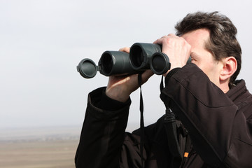 Obraz premium Man looks through binoculars