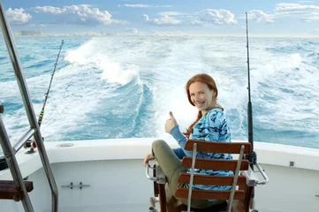 Fotobehang fisherwoman big game on boat chair ok sign © lunamarina
