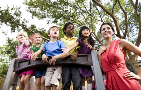 Preschool children playing on playground with teacher