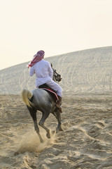 Obraz premium Arab Man Riding A Horse In The Desert
