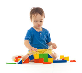 Cute little boy is playing with colorful building wooden blocks