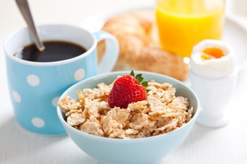 Frühstück mit Cornflakes, Kaffee, Croissant und Ei