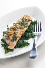 grilled salmon with herbs on fried spinach