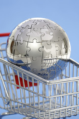 Metal puzzle globe with shopping cart on blue background