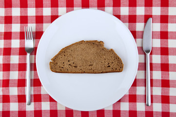 Tablecloth with fork, knife and a slice of bread on the plate