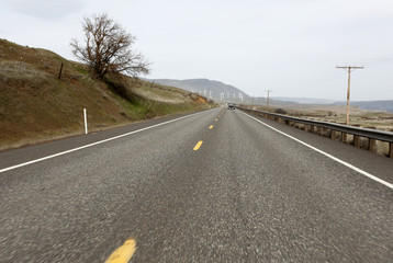 Fototapeta premium Rural highway with a windfarm up ahead.