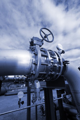 Obraz premium industrial pipelinesand valve on pipe-bridge against blue sky