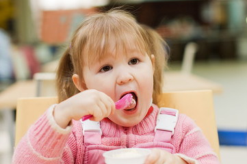 Fototapeta premium The little girl eats ice-cream