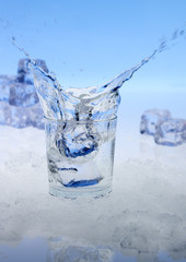 Eiswürfel fallen in ein Glas Wasser