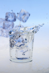Eiswürfel fallen in ein Glas