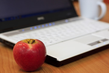 Red apple beside the a notebook in an office