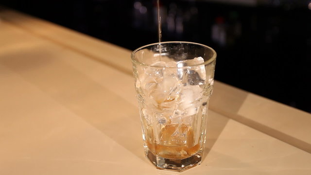 filling a glass full of ice with liqueur