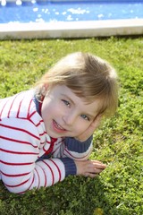 blond little girl laying on pool grass posing