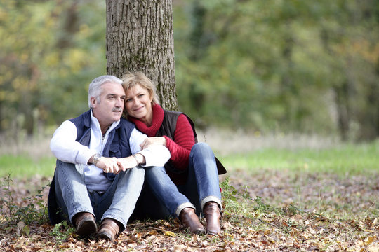 Couple assis près d'un arbre à la campagne