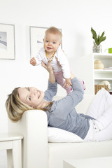 junge mutter mit baby auf weißem sofa