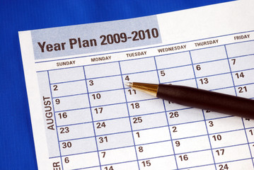 Planning the year on the day planner isolated on blue