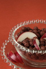 Chocolate cereals with slices of red apple