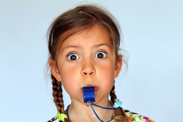 Young girl blowing a whistle as hard as she can