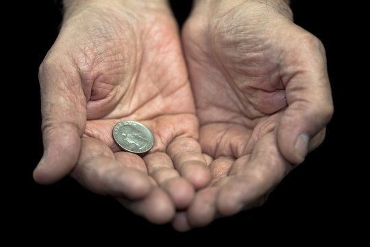 Poverty. Old hands with a single coin of 25 cents