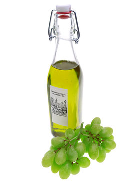 eine Flasche Traubenkernöl mit frischen grünen Trauben im Hintergrund