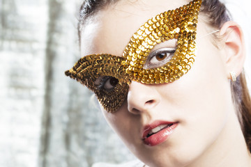 Cute young woman wearing golden mask