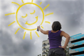 woman painting the sun onto the cloudy sky