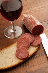 slice salami and bread with glass of red wine