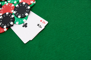Two aces and gambling chips on green casino felt background