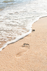 Ocean wave wash away footprints on sand