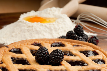 blackberry pie with flour and egg on background
