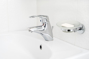 One chrome faucet in washbowl in bath room with soap holder