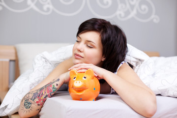 junge frau mit sparschwein im bett