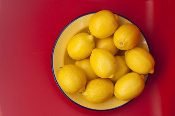 bowl of lemons against red background